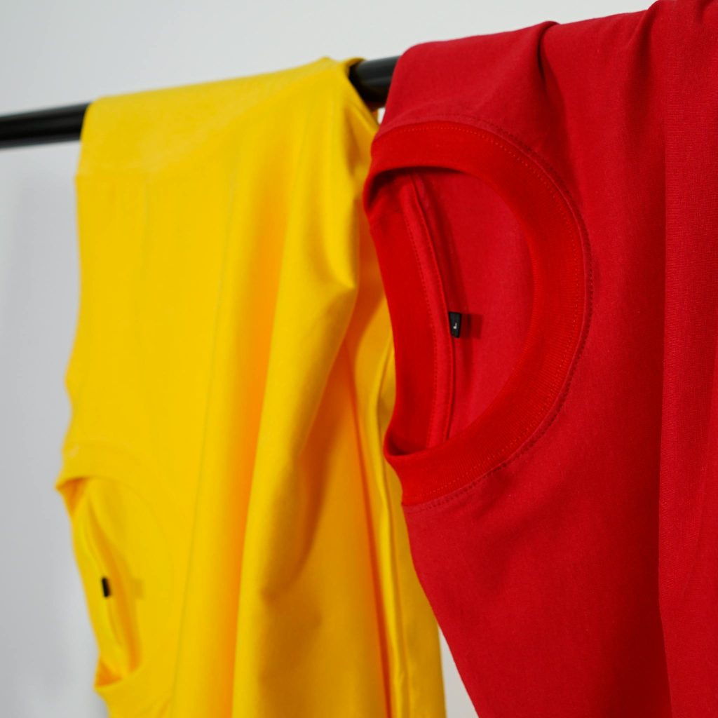 Maximizing Your Blog’s Reach: SEO Tips for Bloggers Red and yellow t-shirts neatly hanging indoors on a black clothing rack.