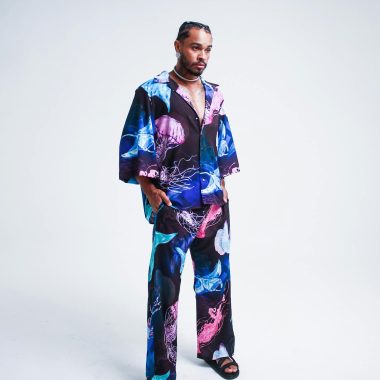 Stylish man posing in a vivid jellyfish-themed outfit against a minimalistic white background.