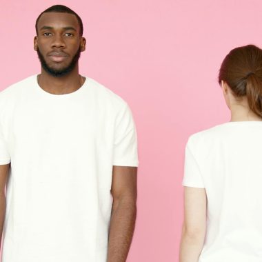 Two models showcasing white t-shirts on a pink background, front and back views.
